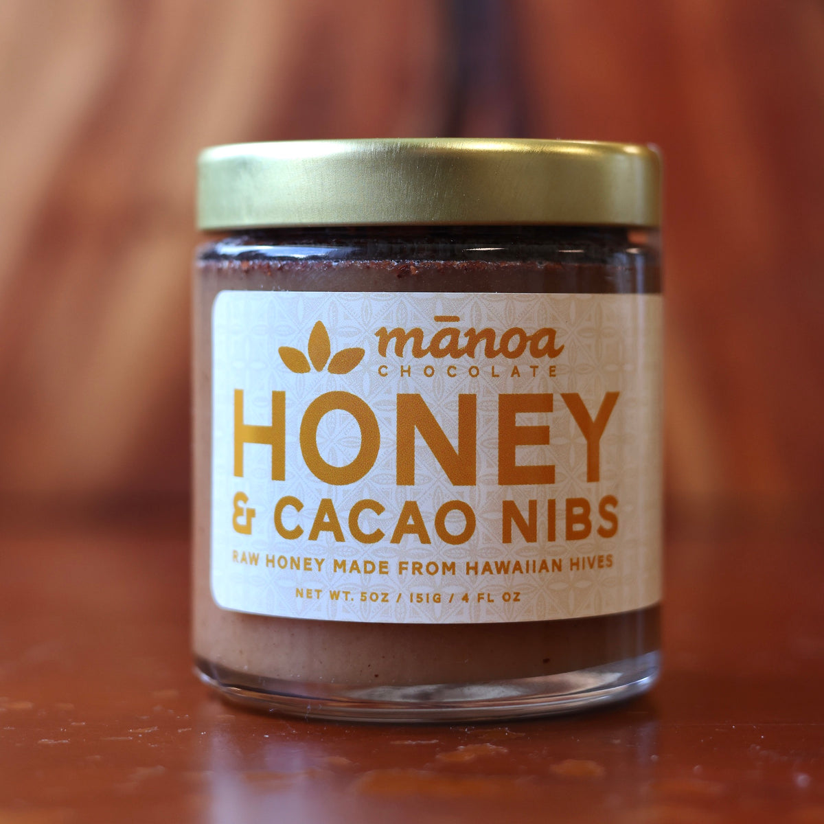 Jar of Manoa Chocolate Honey & Cacao Nibs on a wooden surface