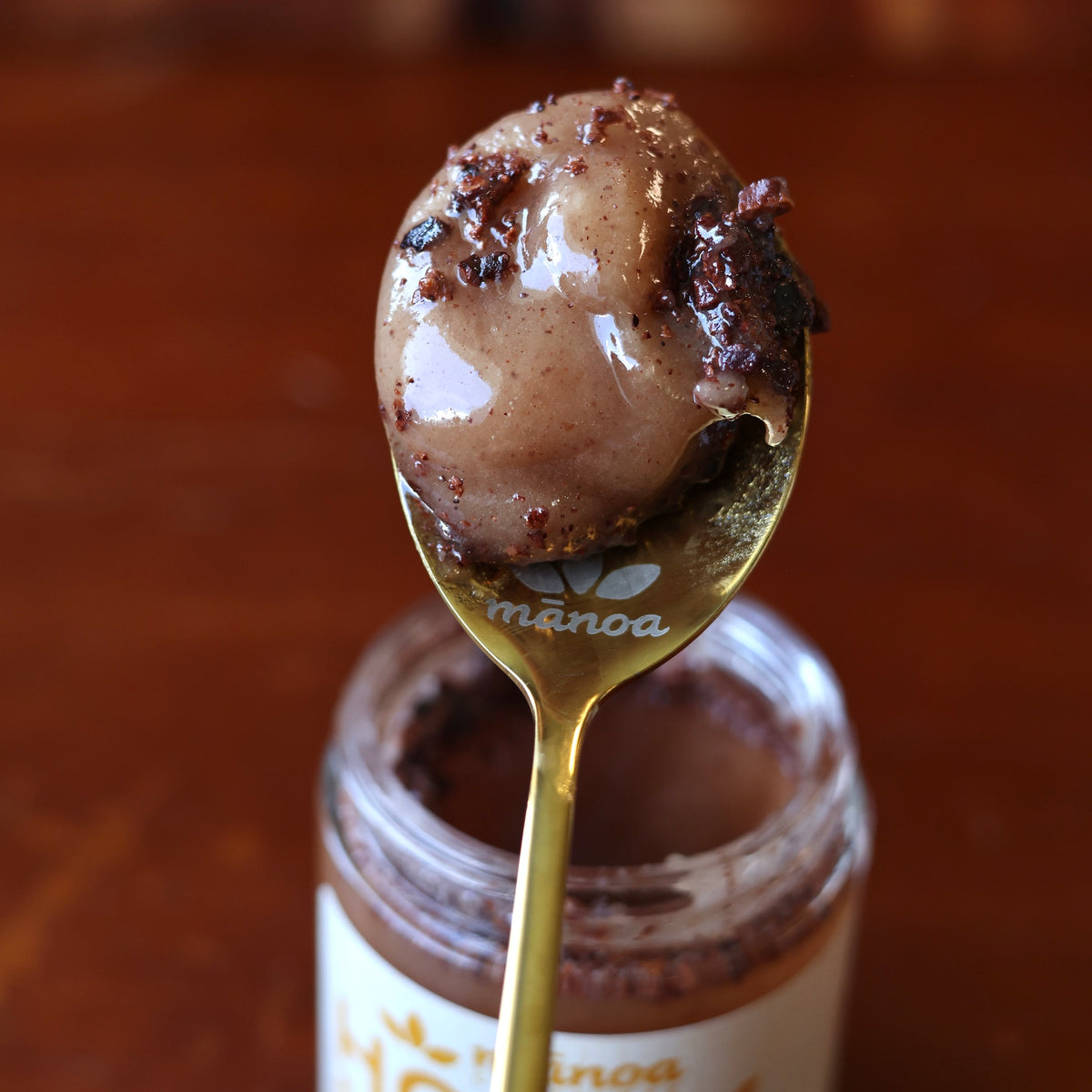 Spoonful of raw honey and nibs on a red wood background