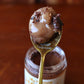 Spoonful of raw honey and nibs on a red wood background