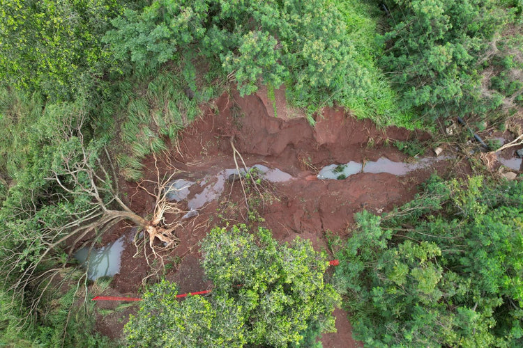 Aerial view of a forest with a cleared area showing red soil.