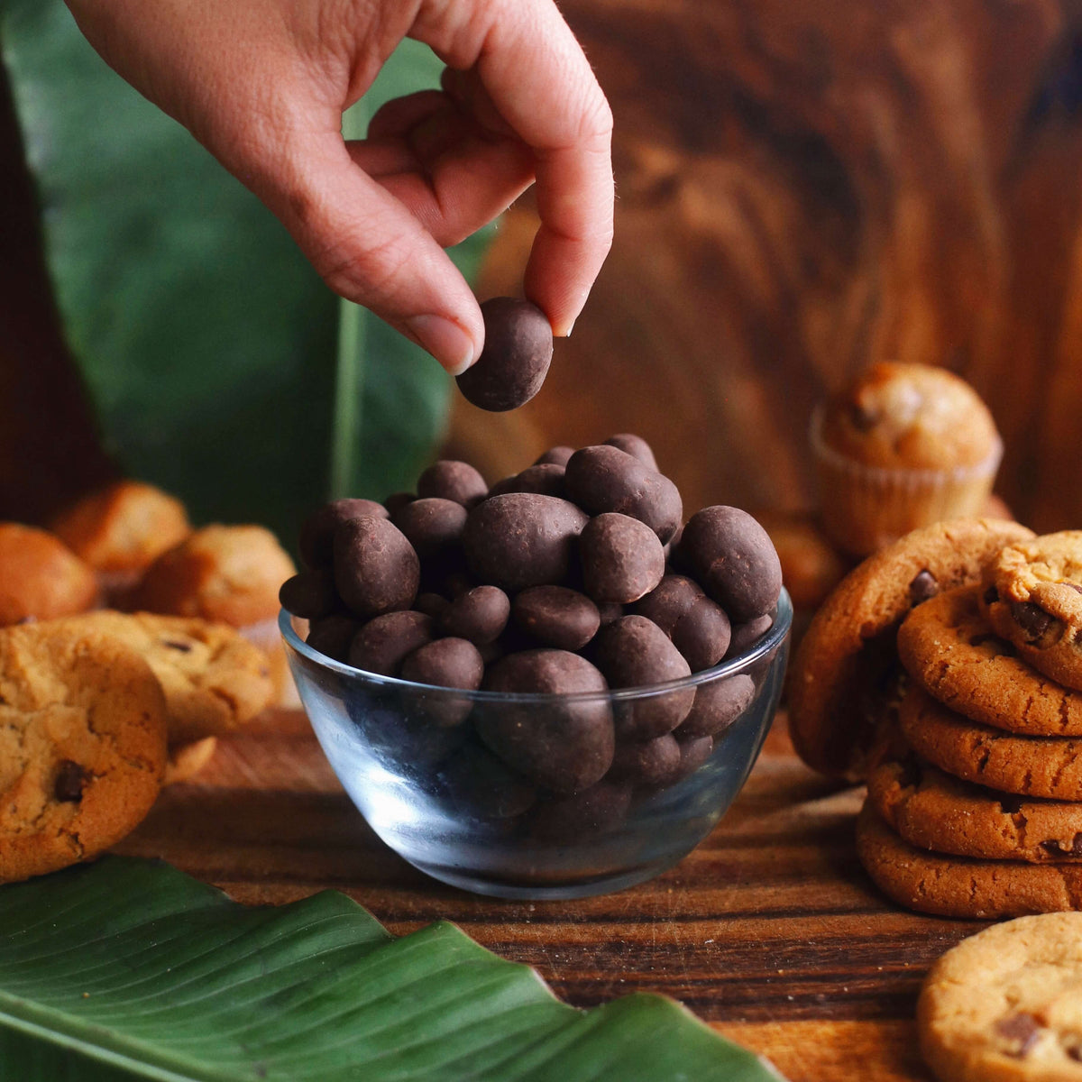 Image of person picking up Kohana dark chocolate macadamia from bowl